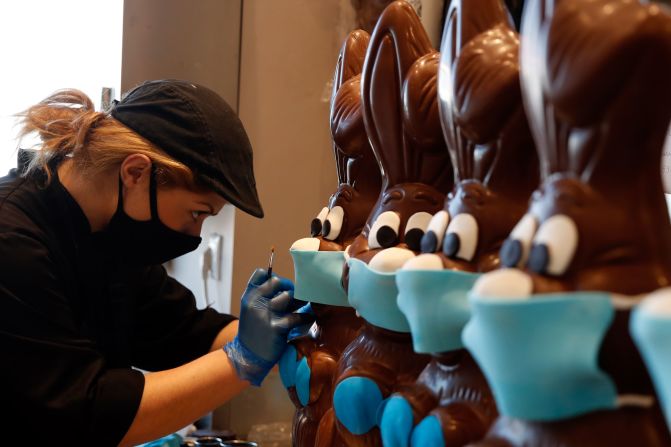 A cake shop employee in Athens, Greece, prepares chocolate Easter bunnies with face masks on April 8, 2020.