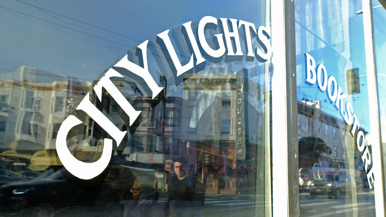 People are reflected in the window of the City Lights Bookstore in North Beach as they walk along Columbus Avenue, Friday, March 13, 2020, in San Francisco. A wave of closures and postponements spanning everything from government offices to cultural events and sports followed California Gov. Gavin Newsom's call this week for cancellation of all non-essential gatherings of 250 people or more because of the coronavirus threat. The vast majority of people recover from the new coronavirus. According to the World Health Organization, most people recover in about two to six weeks, depending on the severity of the illness. (AP Photo/Eric Risberg)