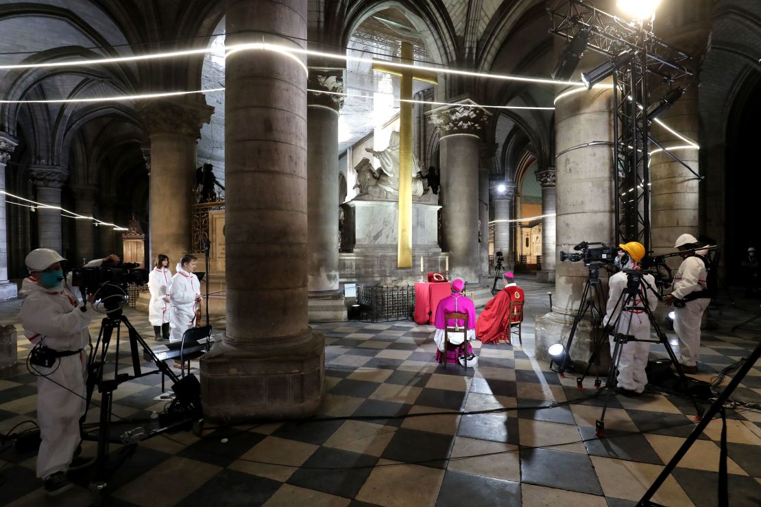Auxiliary Bishop of Paris Denis Jachiet, center, and Archbishop of Paris Michel Aupetit, left, attend a meditation ceremony to celebrate Good Friday in a secured part of Notre Dame.