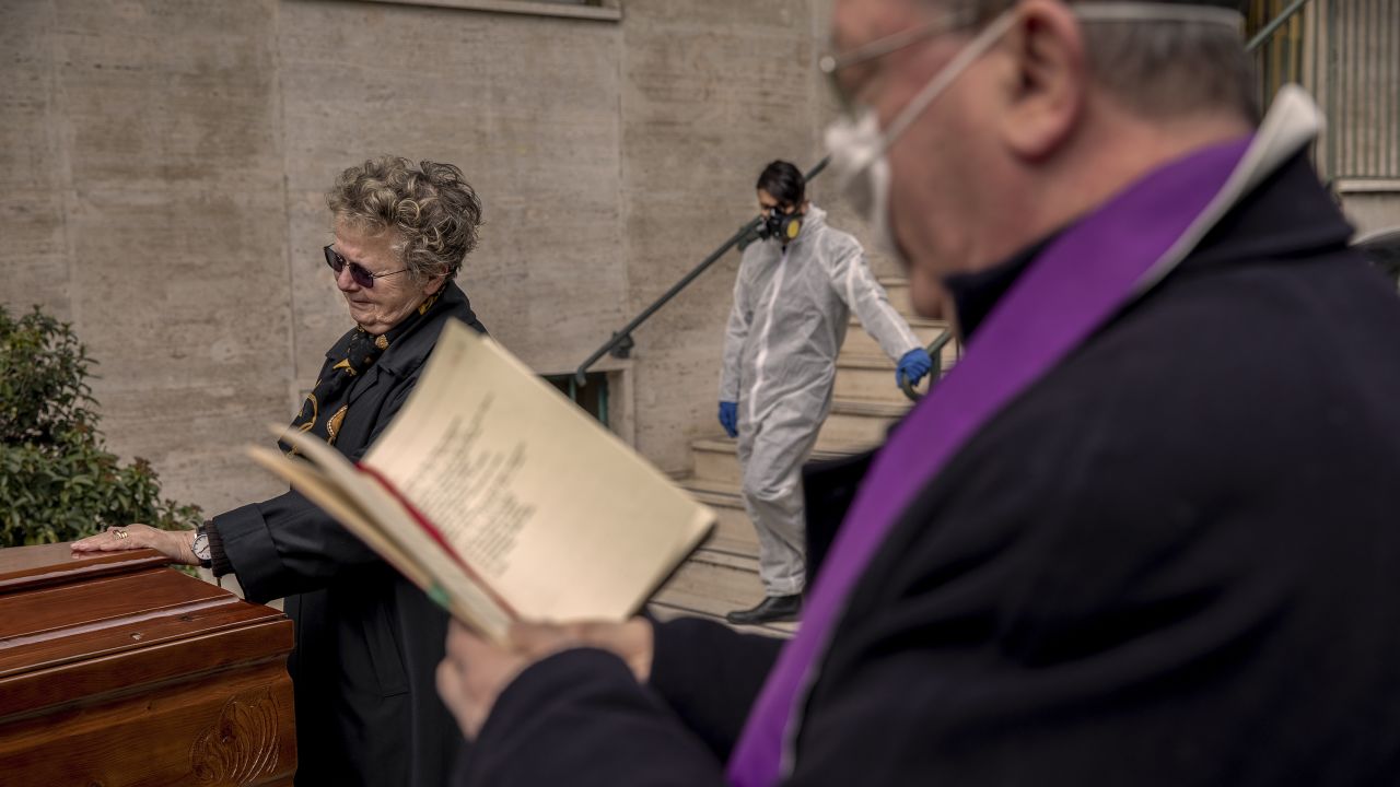A priest wearing a mask blesses a coffin inside the courtyard of a building in Naples, Italy, on March 27.