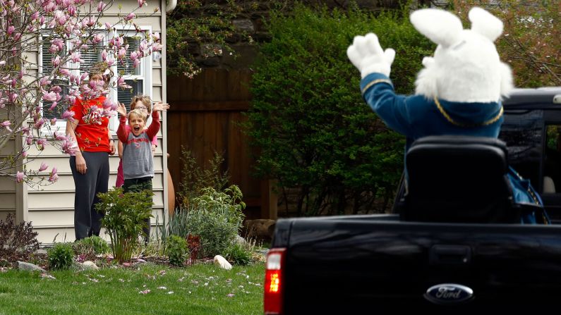Children wave to a person dressed as the Easter Bunny during a neighborhood parade in Haverford, Pennsylvania, on April 10, 2020.