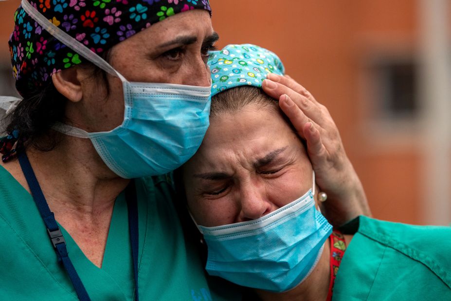 Health workers in Leganes, Spain, cry during a memorial for a co-worker who died because of the coronavirus.