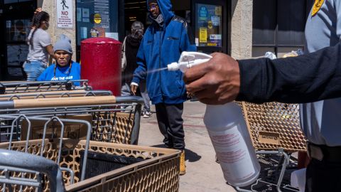 A Safeway security guard sprays bleach on a shopping cart on April 11, 2020, in Winslow, Arizona, where Navajos go to stock up on food and seek medical help.