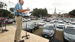 Pastor Cliff Lea preaches over a parking lot filled with cars during a drive-in service at the First Baptist Church of Leesburg on Easter Sunday, April 12, 2020. With coronavirus prevention measures shuttering houses of worship, pastors across the country are urging parishioners to use their cars to safely bring their communities closer together.  Drive-in churches are popping up so worshipers can assemble. (Stephen M. Dowell/Orlando Sentinel via AP)