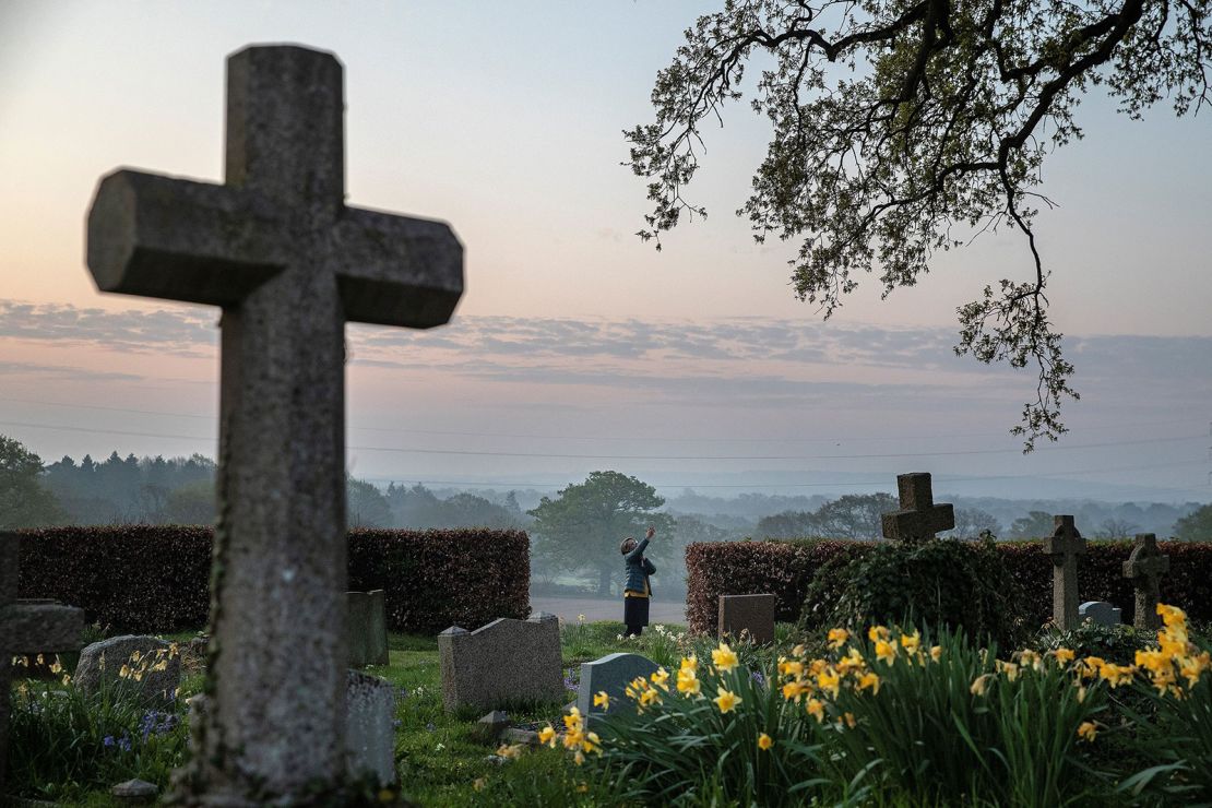 Priest-in-Charge Angie Smith uses her smartphone to live-broadcast an Easter Sunday service to her congregation from the churchyard of Old St. Mary's Church in Hartley Wintney, west of London, on April 12, 2020. 