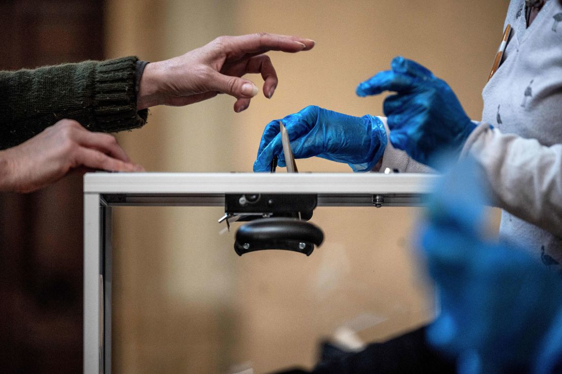 A voter casts their ballot in front of an official wearing plastic gloves in a polling station in Lyon on March 15. 