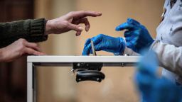 A voter casts their ballot in front of an official wearing plastic gloves in a polling station of Lyon on March 15, 2020 during the first round of the mayoral elections. 