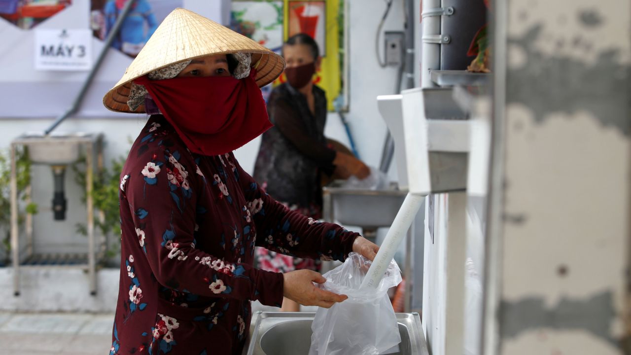 A woman fills a plastic bag with rice from a 24/7 automatic rice dispensing machine in Ho Chi Minh City, Vietnam, on April 11, 2020.