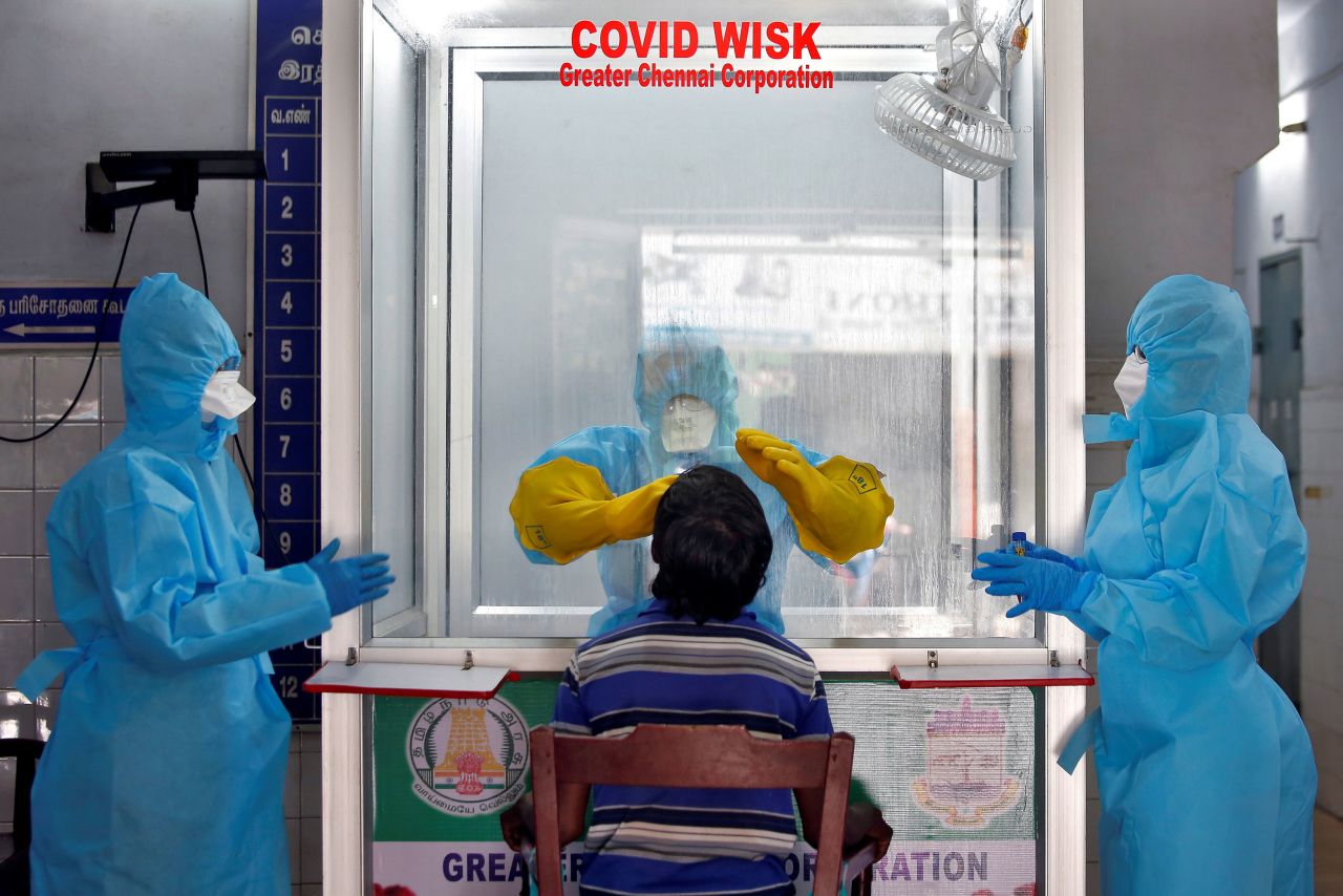 A doctor in a protective chamber tests a patient for coronavirus at a walk-in kiosk in Chennai, India.