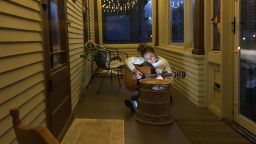 Steve Schneider's 18-year-old daughter plays her guitar on their porch in Sheboygan, Wisconsin. 