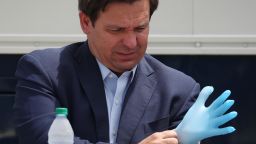 Florida Gov. Ron DeSantis puts on a rubber glove before the start of  a press conference at the Miami Beach Convention Center on April 08, 2020 in Miami Beach, Florida. Gov. DeSantis spoke about the U.S. Army Corp. of Engineers converting the convention center into a field hospital with 400 regular hospital beds and 50 ICU beds, with the ability to scale up to 1,000 beds if needed, as the region prepares for a possible surge of coronavirus patients.