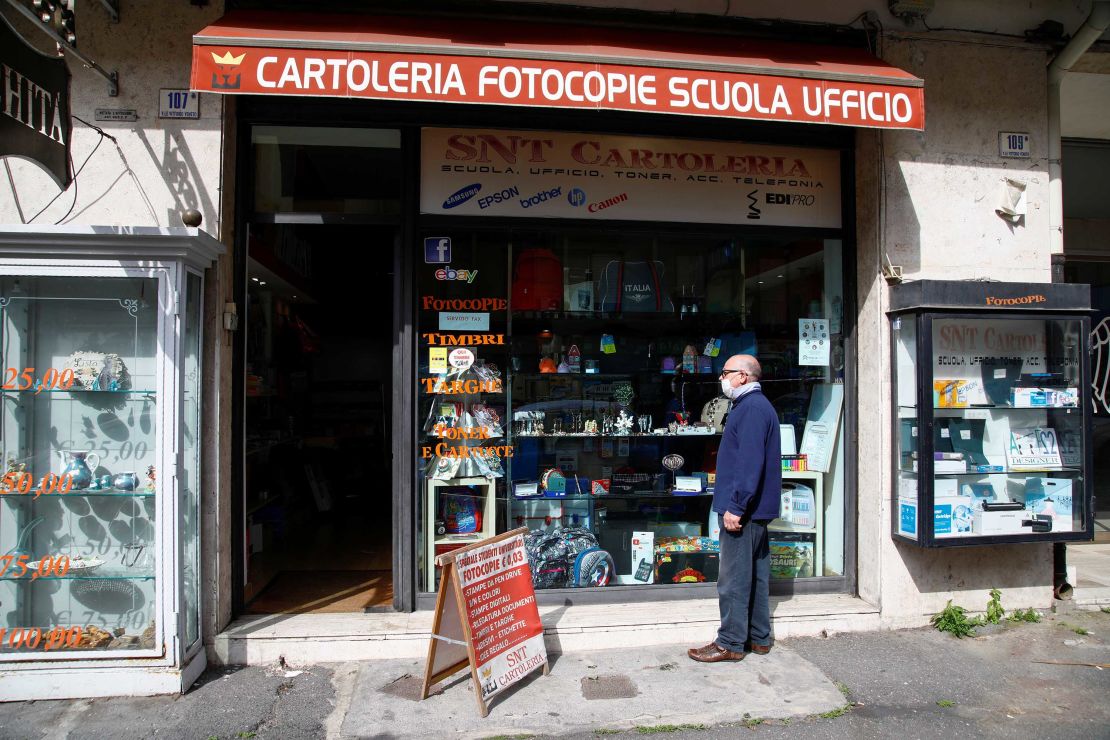 A man wearing a face mask stands in front of the store in in Catania, Italy, on April 14 as the government allows the reopening of some stores while a nationwide lockdown continues.