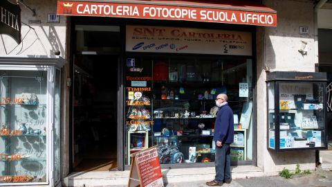 A man wearing a face mask stands in front of the store in in Catania, Italy, on April 14 as the government allows the reopening of some stores while a nationwide lockdown continues.