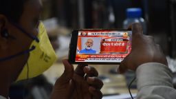 A man wearing a facemask as a preventive measure against COVID-19 coronovirus listens to India Prime Minister Narendra Modi's address to the nation on his mobile phone on March, 19, 2020. 