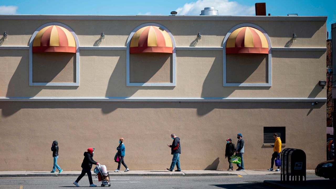 People keep social distance as they queue in front of the supermarket on April 11, 2020, in New York City. - The US overtook Italy on April to become the country with the largest death toll in the coronavirus pandemic, according to a tally kept by Johns Hopkins University. On april 10, the US reported 2,108 new deaths, the highest daily toll out of any country since the outbreak was first reported. (Photo by Johannes/AFP/Getty Images)