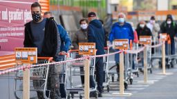 Customers wearing face masks and pushing shopping carts line up in front of a DIY store in Innsbruck, Austria, after it re-opened on April 14.
