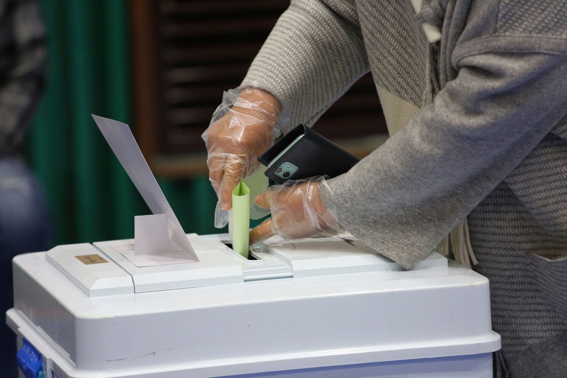 A voter wearing plastic gloves to help protect against the spread of coronavirus casts a vote for the parliamentary election at a polling station in Seoul.