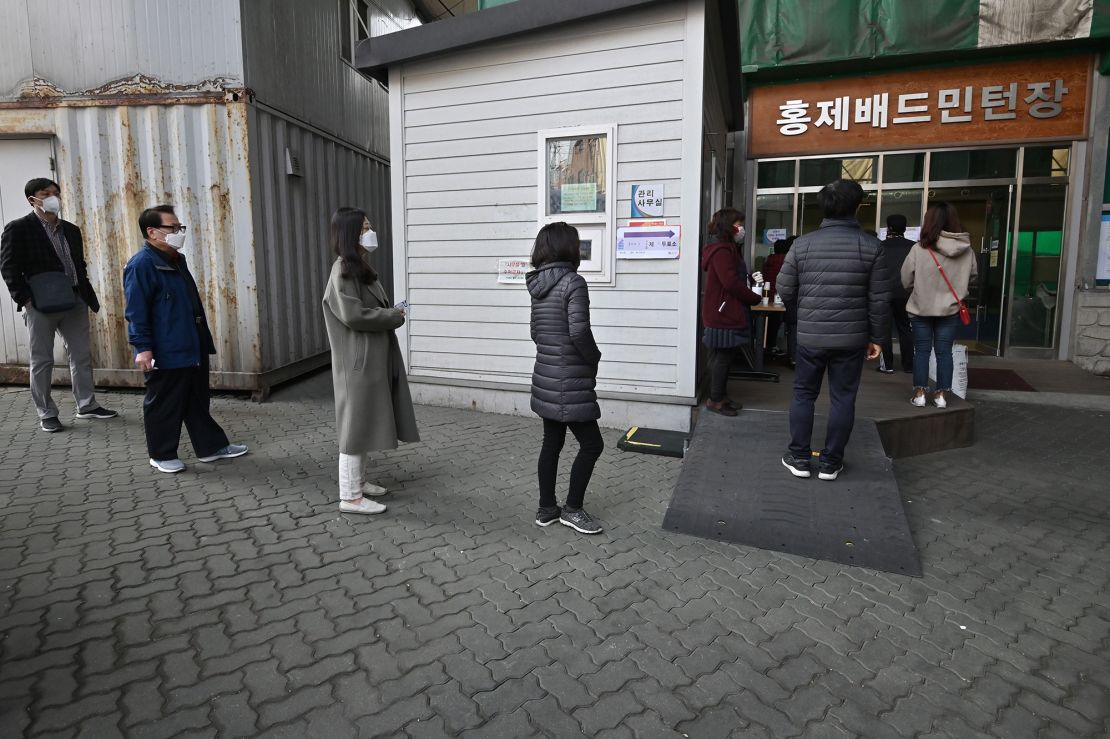 South Koreans wait in line to cast their ballots for the parliamentary elections at a polling station in Seoul. 