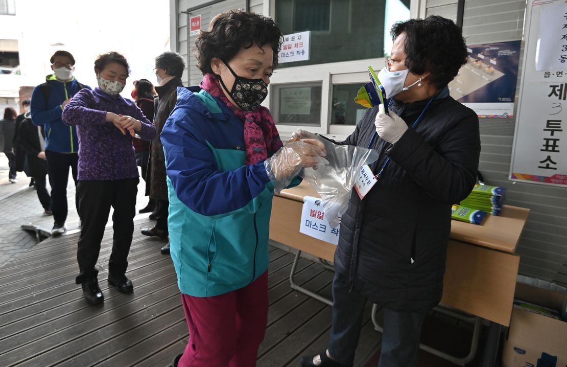 A South Korean woman wears plastic gloves and a mask as she prepares to cast her ballot during April's election. 