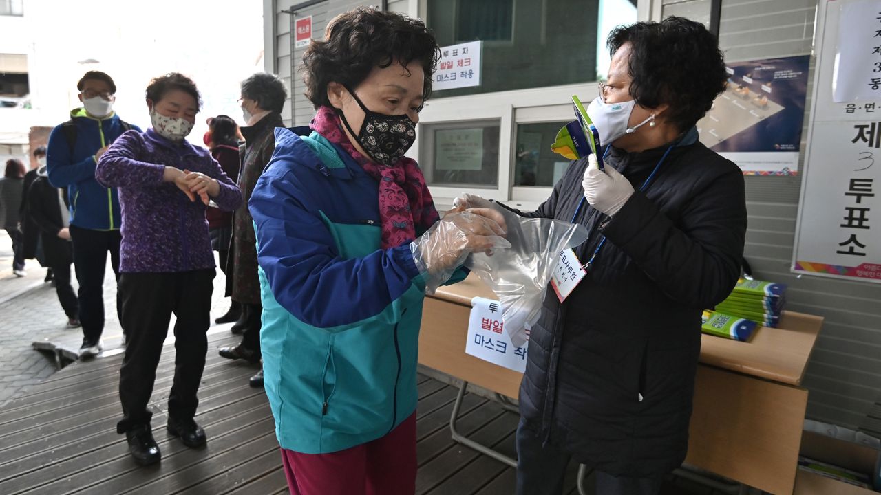 A South Korean woman wears plastic gloves and a mask as she prepares to cast her ballot during April's election. 