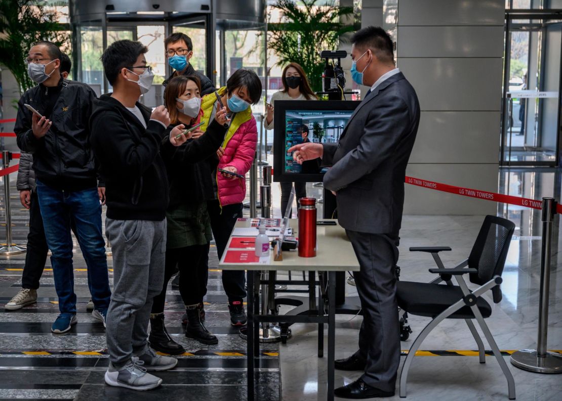 Chinese office workers show their mobile phones with their health code to a guard, which shows they have permission to travel and are virus free, as they arrive at an office building on April 10.