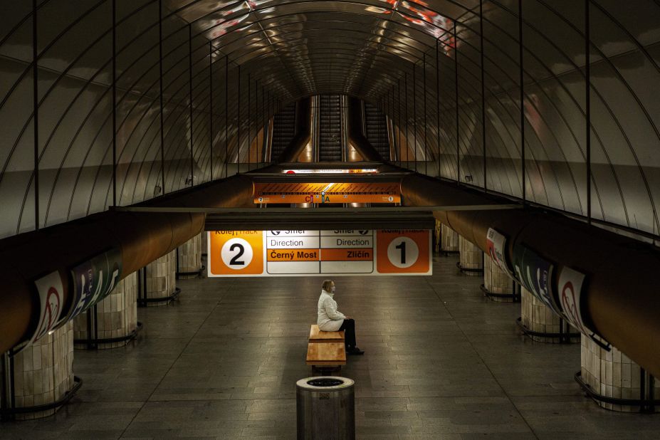A woman sits on a bench at an empty metro station in Prague, Czech Republic.