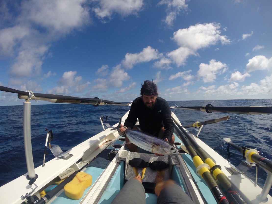 Riaan Manser holding a fish on his row boat