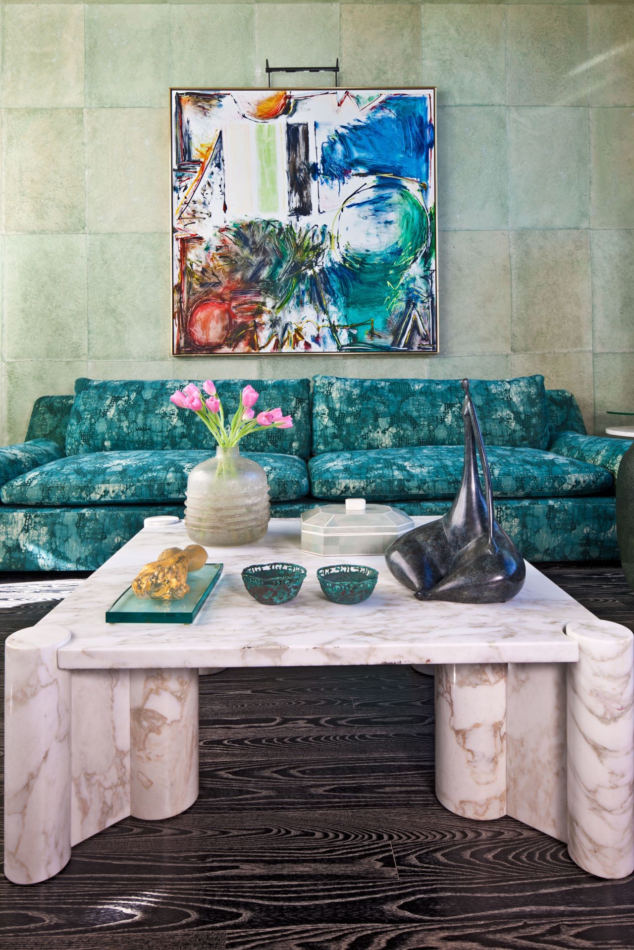 This room in a triplex apartment in New York City has an intimate seating area with a monochromatic palette in hues of teal and mineral fabric by Kelly Wearstler. The walls are covered in vegetable-dyed handmade paper by Cannon Bullock.