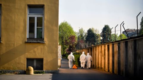Staffers wearing protective outfits walk at the Pio Albergo Trivulzio nursing home in Milan on Tuesday, April 7, 2020.