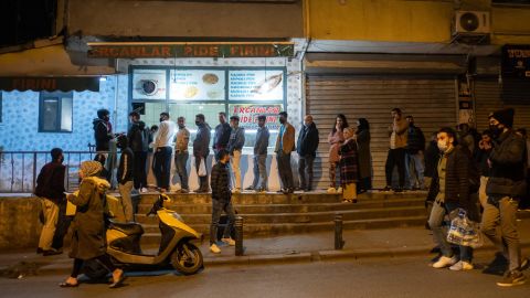 People queue at shops for food shortly before the curfew in Istanbul, on April 10, 2020.