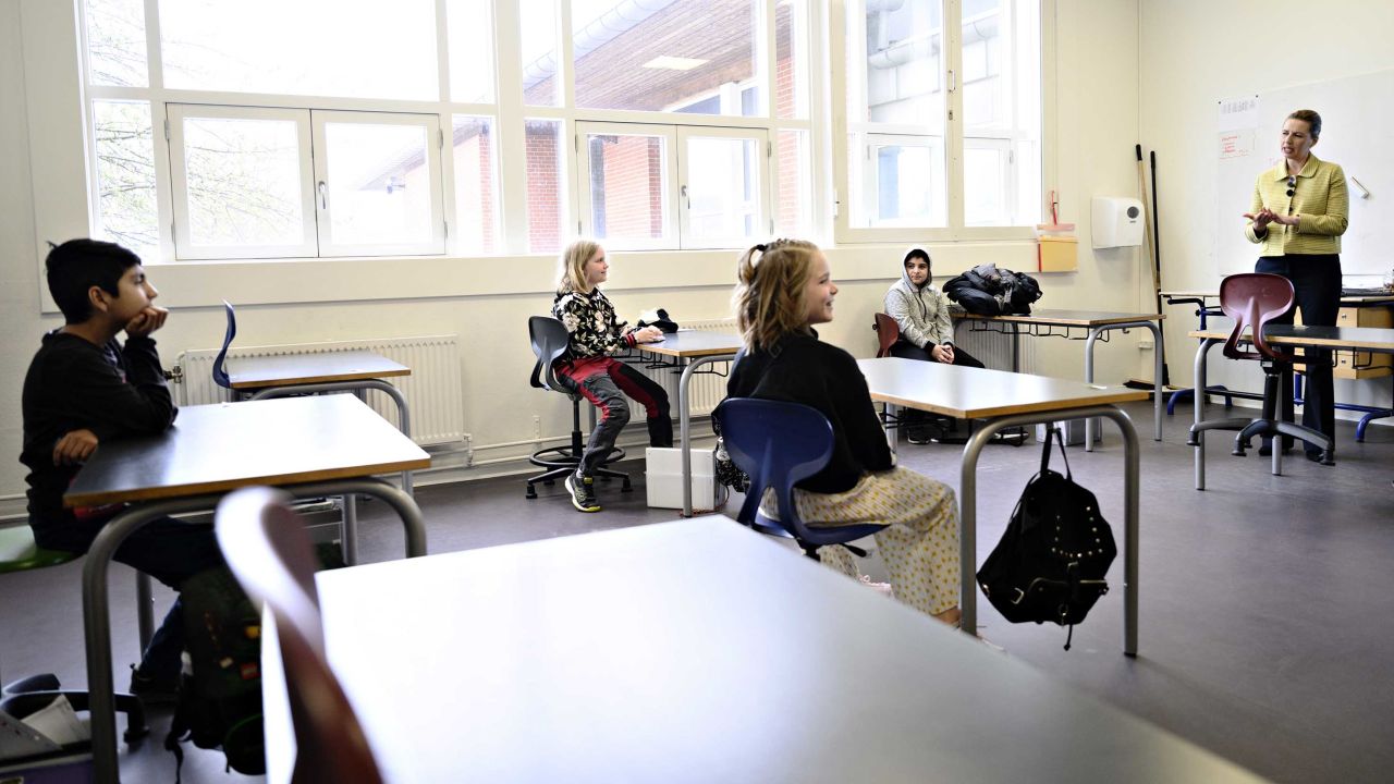 Denmark's Prime Minister Mette Frederiksen, right, speaks to students sitting two meters away from each other during the reopening of Lykkebo School in Copenhagen.