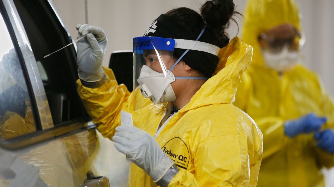 Registered nurse Raquel Hernandez reaches in to swab a passenger for a Covid-19 test at a mobile testing site in Sulphur, Oklahoma, on Tuesday, April 14, 2020. 
