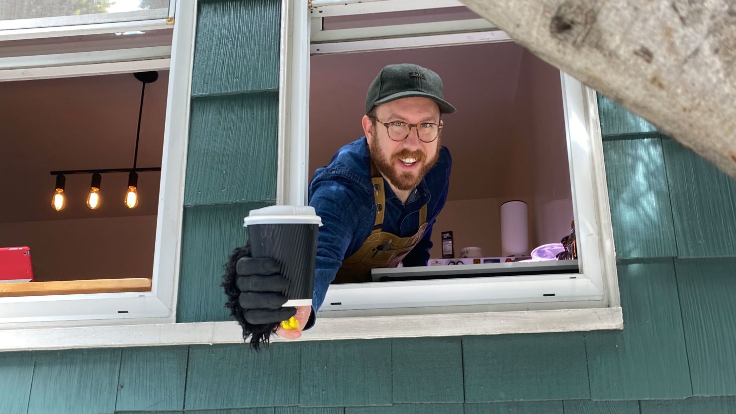 Ben Ramirez hands out free cups of coffee to essential workers and neighbors in San Francisco. He keeps a safe distance with the help of a toy gorilla hand.