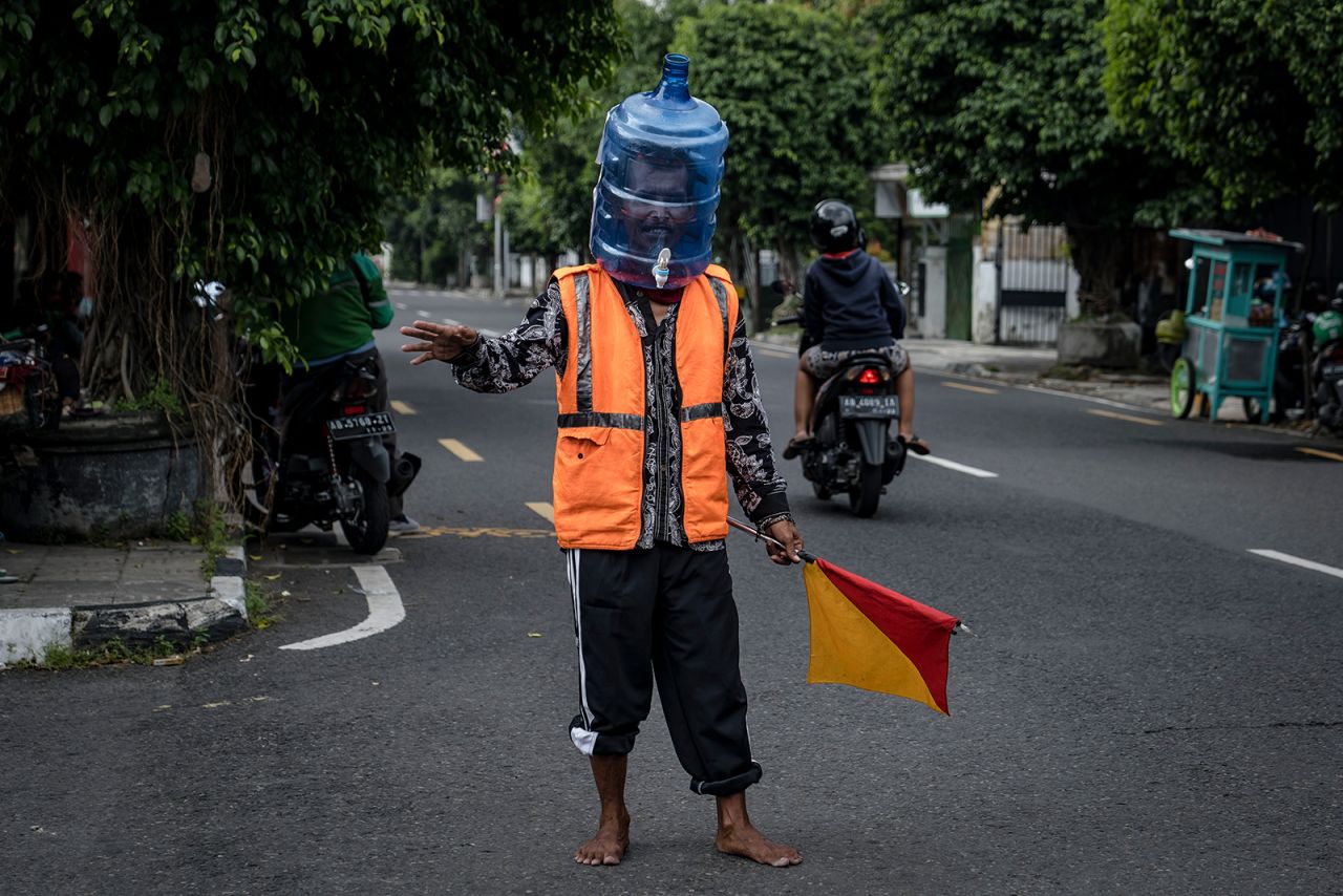 Ali Akbar, a street parking man in Yogyakarta, Indonesia, wears a face shield made from a used water jug.
