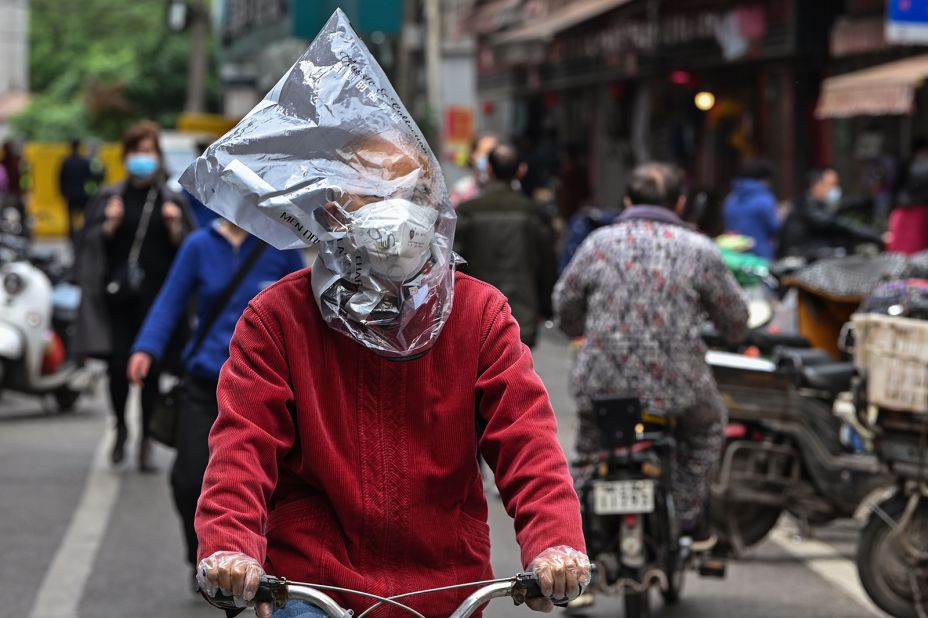 A cyclist in Wuhan, China, wears a face mask and plastic bag.