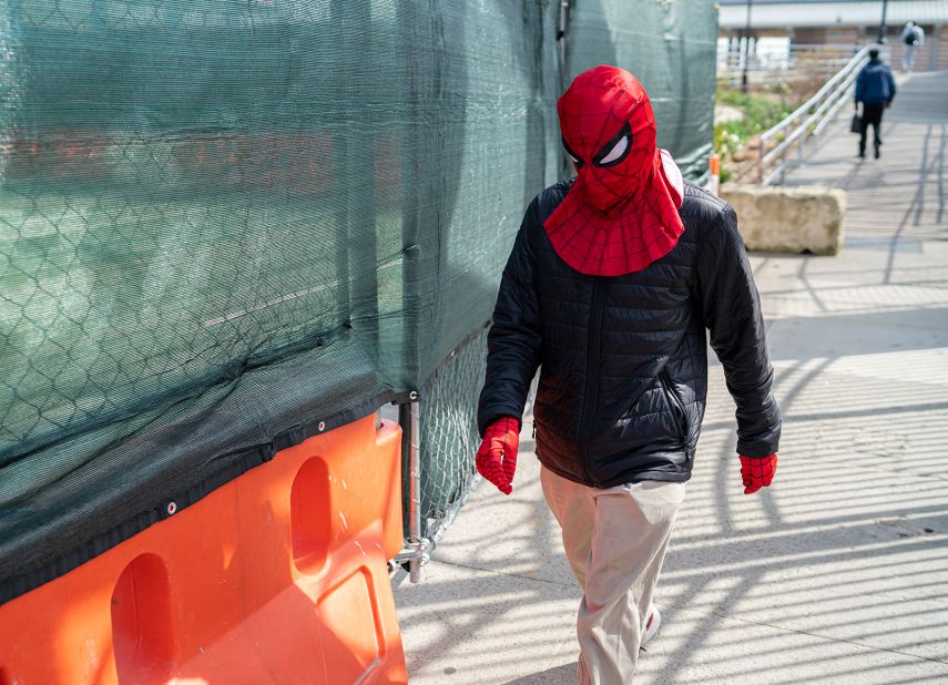 A man wearing a Spider-Man mask and gloves walks near the Coney Island boardwalk in New York.
