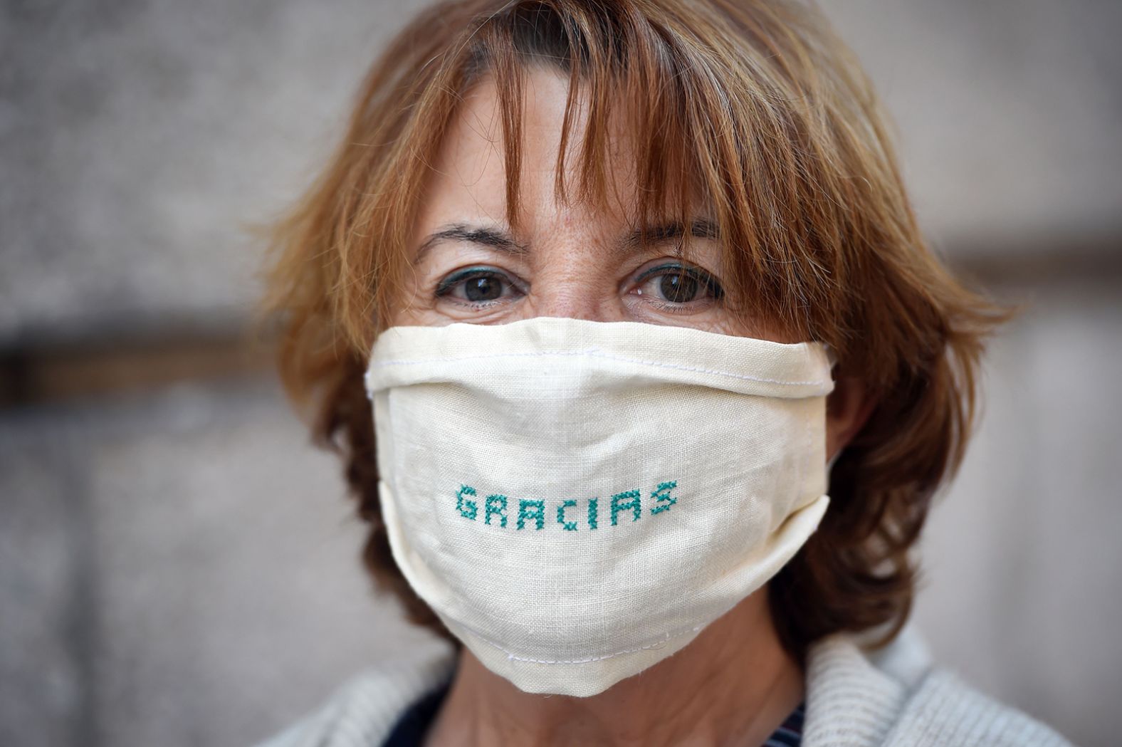 A woman in Coruna, Spain, wears a mask with the word "thanks" embroidered on it.