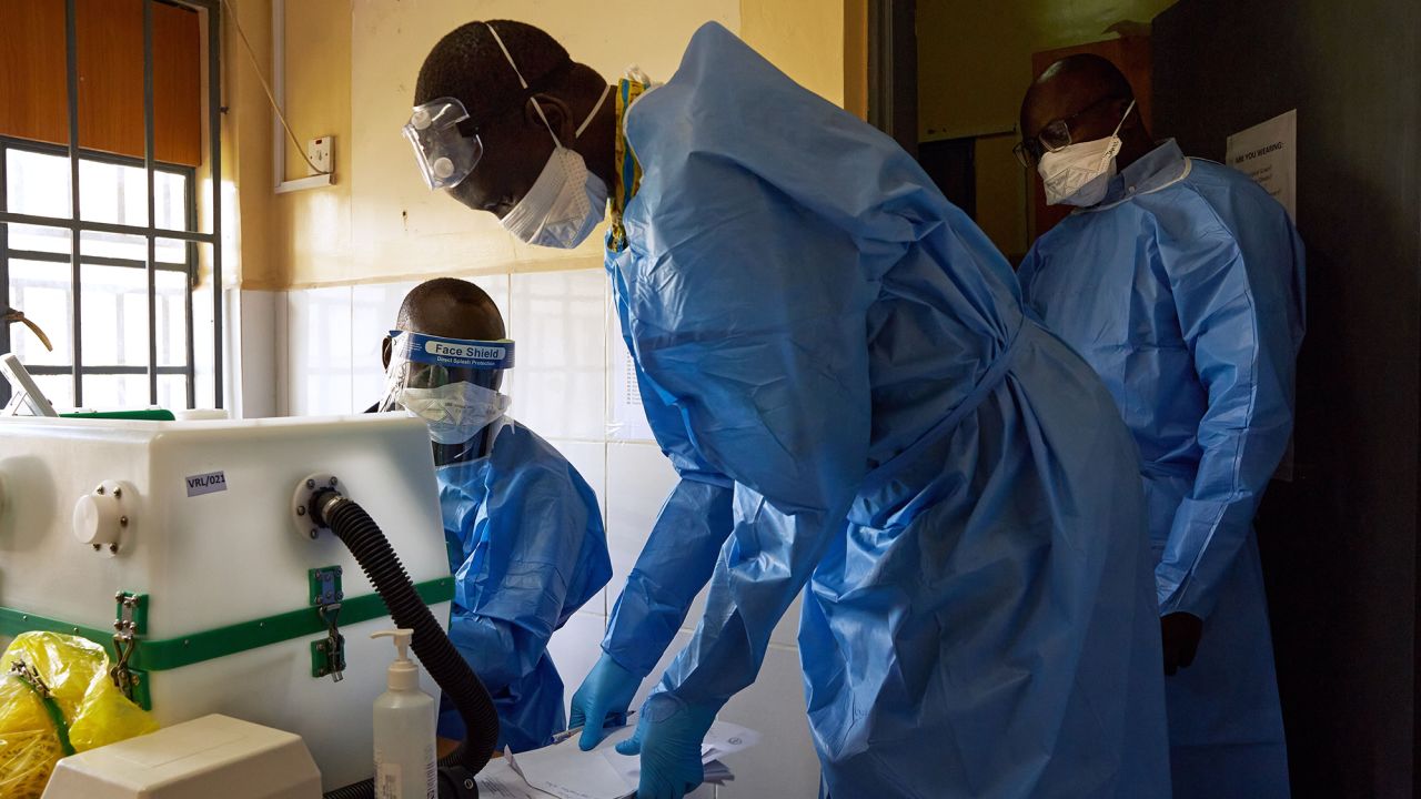 Lab technicians gather around a machine as they