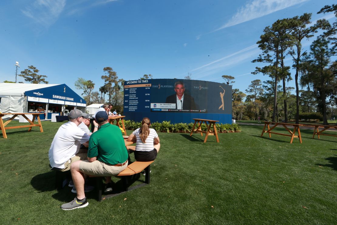 Fans watch on video screens as Monahan speaks to the media in a press conference announcing fans will no longer be allowed to attend PGA tour events.