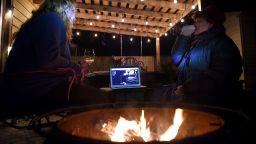 Neighbors sit around a fire-pit to watch Eddie Vedder perform during the "One World: Together at Home" concert in a backyard on April 18, 2020, in Arlington, Virginia. - A star-studded digital show got underway with celebrities performing from their homes in support of health workers, ahead of an all-star event to feature Taylor Swift and The Rolling Stones. (Photo by Olivier DOULIERY / AFP) (Photo by OLIVIER DOULIERY/AFP via Getty Images)