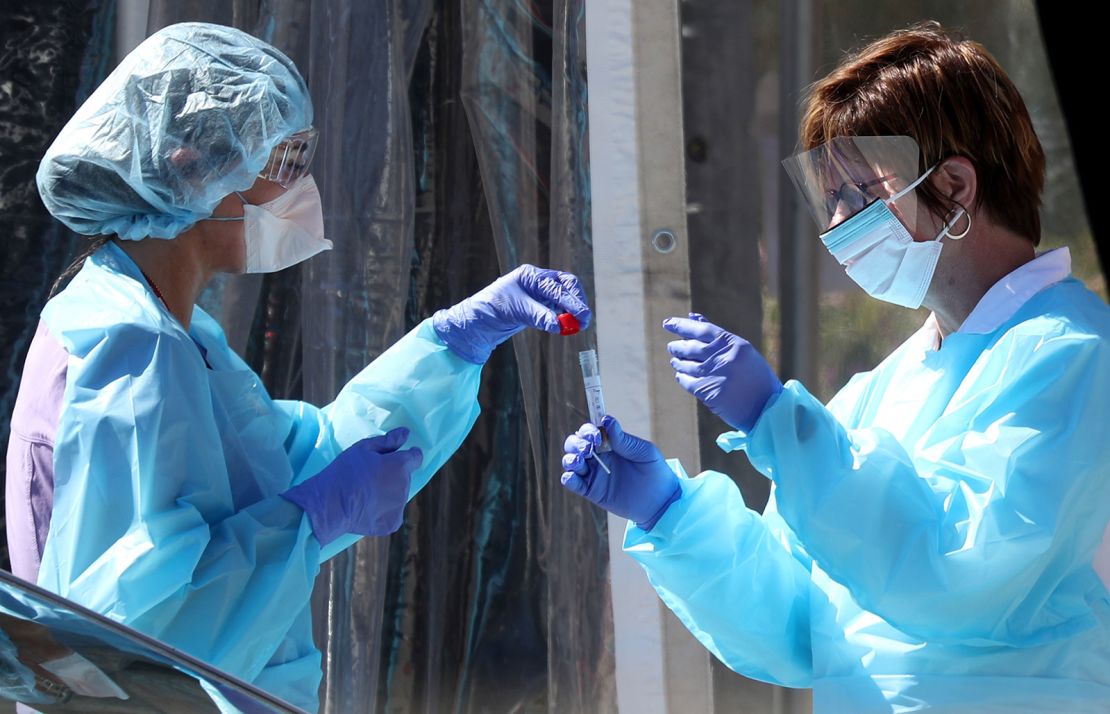Medical personnel in San Francisco secure a sample from a person at a drive-thru coronavirus testing station in March.  (Photo by Justin Sullivan/Getty Images)