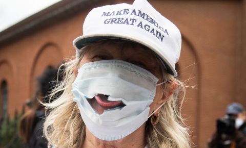 A woman sticks her tongue out of a torn mask at a Reopen Maryland rally outside the State House in Annapolis, Maryland, on April 18, 2020. Residents in multiple states were protesting stay-at-home orders.