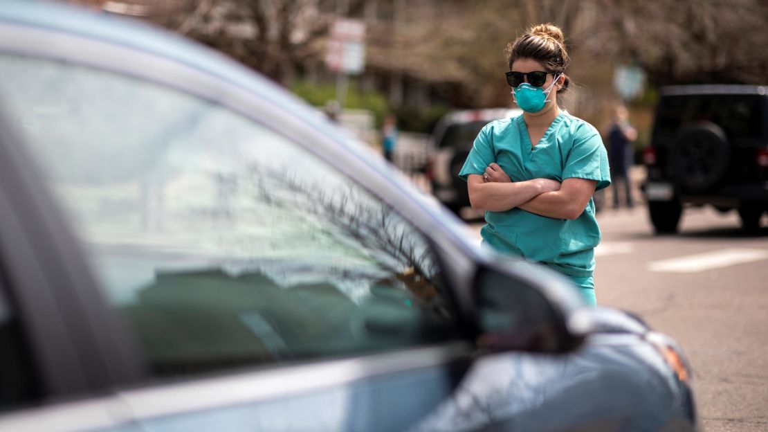 A health care worker  counterprotests at a rally demanding Colorado ease its stay-at-home order.