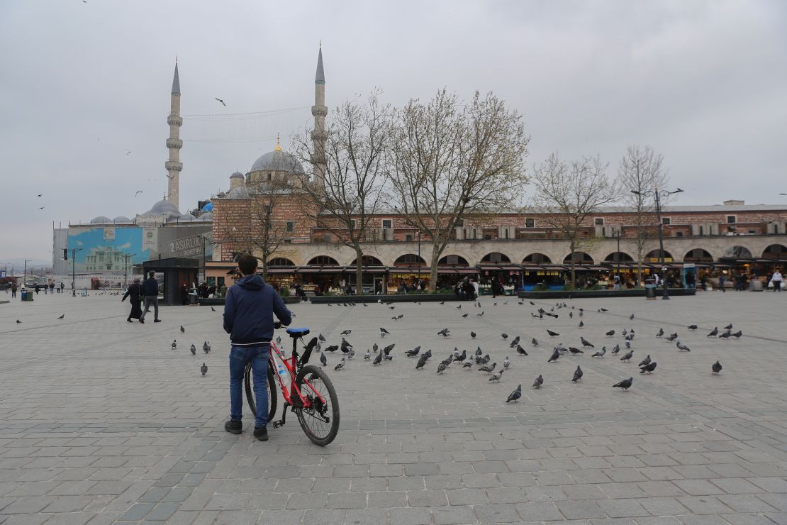 A man with his bike surrounded by pigeons in a nearly empty Yenicami Square, at the Spice Bazaar in Istanbul, Turkey, during the weekend lockdown.