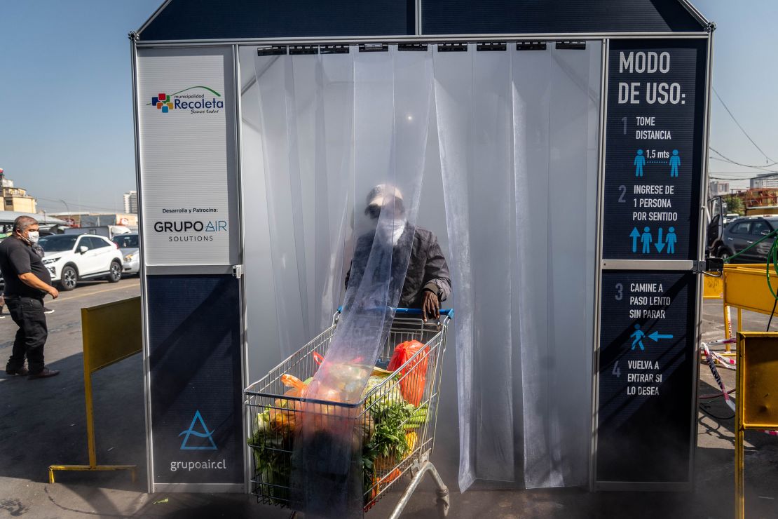 A person wearing a protective mask pushes a grocery cart through a decontamination chamber at the La Vega Central fruit and vegetable market in Santiago, Chile.