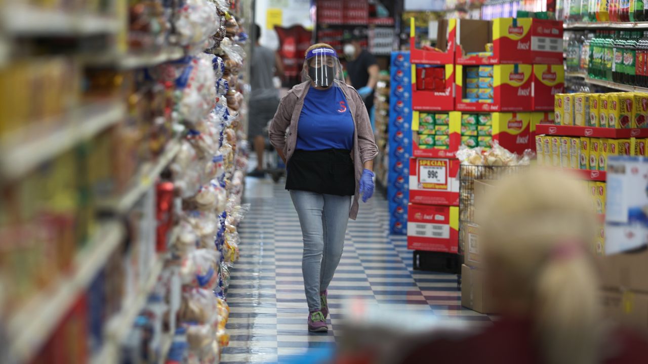 Yaleidis Santiago wears a full face shield, mask and gloves as she works at the Presidente Supermarket on April 13, 2020 in Miami, Florida.
