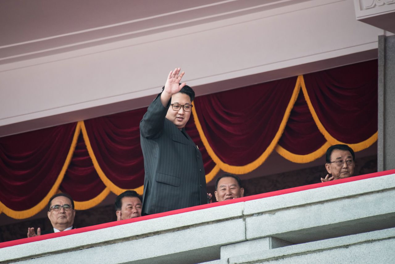 Kim waves as he walks past top-ranking party officials during a parade in Pyongyang in May 2016.