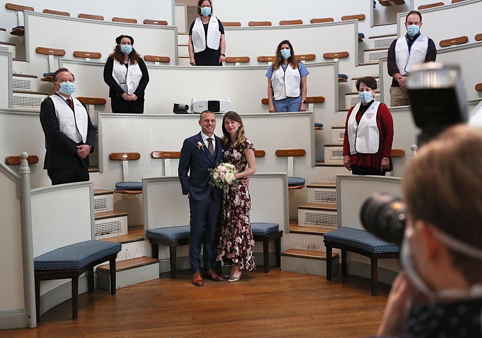 Matt Shearer and Jen Andonian get married at the Massachusetts General Hospital Ether Dome in Boston on March 27. They are both epidemiologists who work in the field of disaster management. Shearer and Andonian were supposed to get married on March 20 in Ann Arbor, Michigan. For their wedding at the MGH Ether Dome, which was once the hospital's operating room, the MGH General Store and Flower Shop did their flowers; Nutrition and Food Service made their cake; and the Photo Lab took the photos and the video to send to the couple's families.