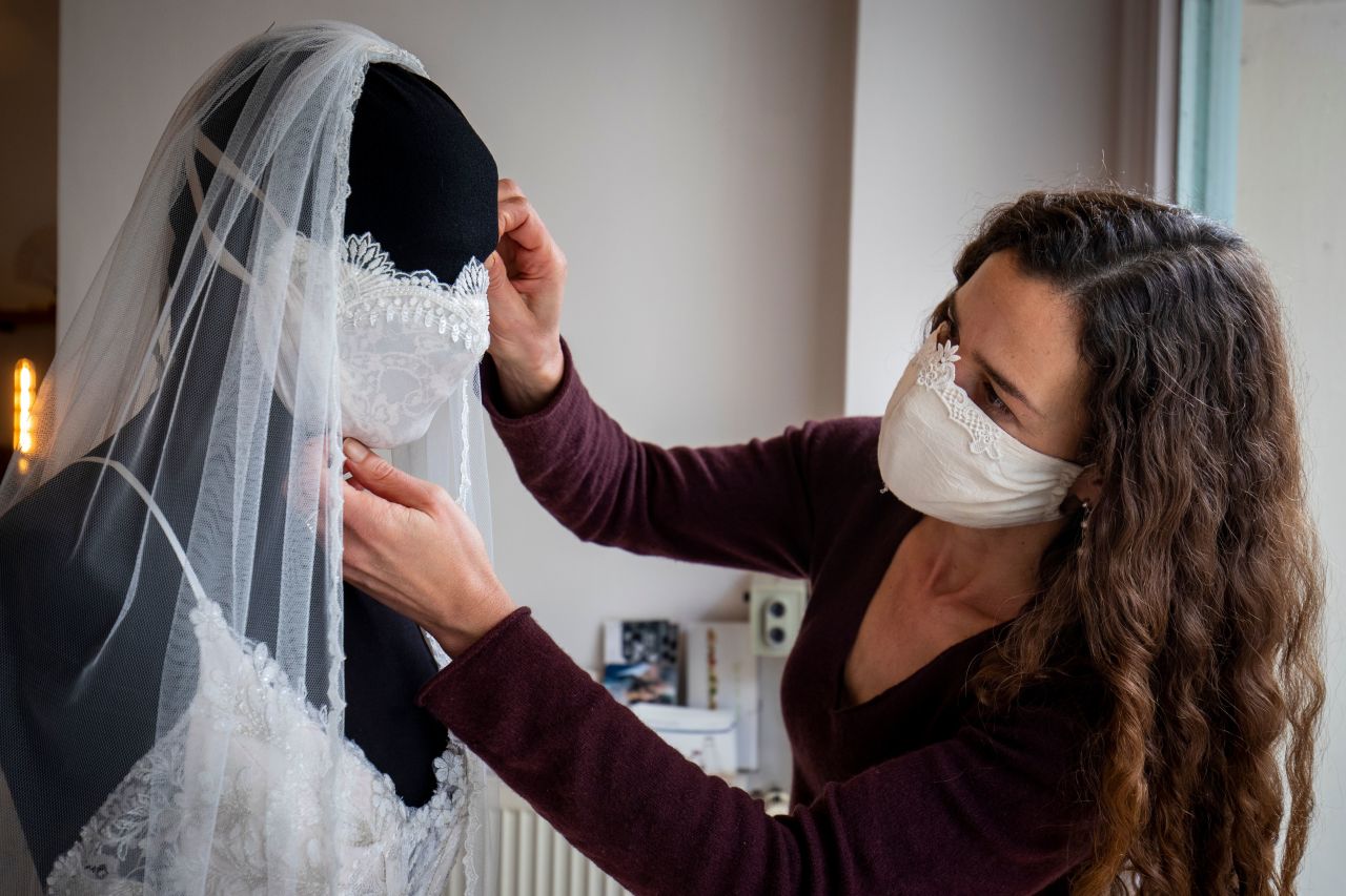 Friederike Jorzig, a wedding dress and evening wear designer, adjusts a mannequin wearing a wedding dress and face mask at her store in Berlin on March 31.