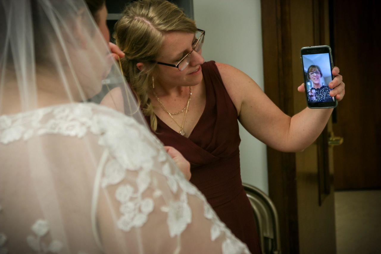 Becky Brown chats with her mom via video before her wedding March 23 at the Eastminster Presbyterian Church in East Lansing, Michigan. She and groom Mike Brown decided to marry that evening after Michigan's "Stay Home, Stay Safe" executive order was issued in the morning, forgoing a ceremony with 120 guests that had been planned for March 28. Her parents dressed up and watched via social media.